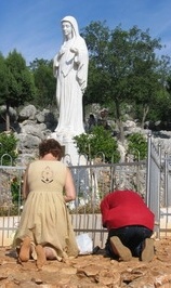 catholic people kneeling and worshiping Mary statue